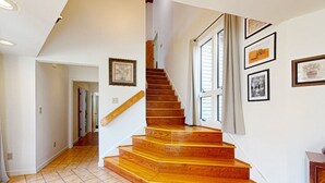 Una escalera de madera con barandilla que lleva a un rellano con una puerta.