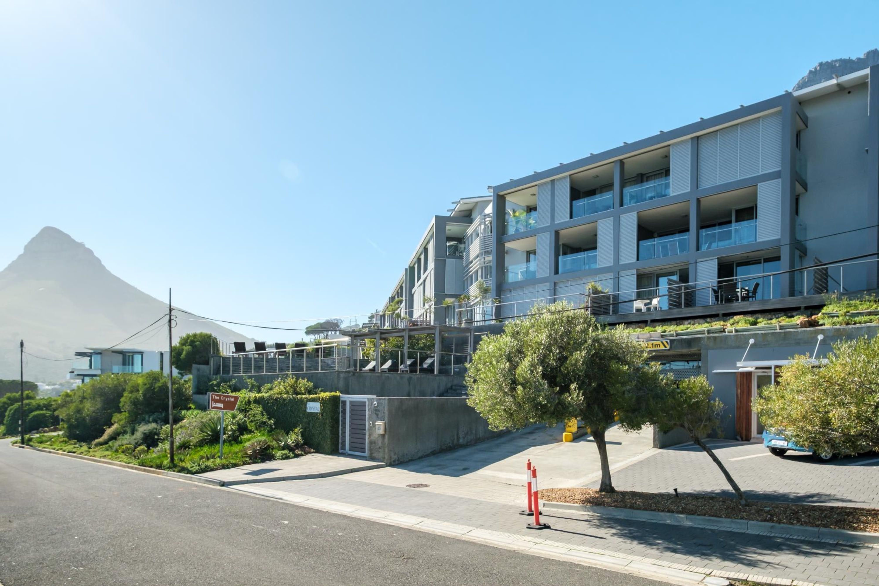Un immeuble moderne à plusieurs étages, doté de balcons, avec un ciel dégagé et une montagne en arrière-plan.