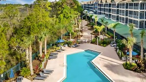Un hôtel doté d’une piscine entourée de chaises longues et de palmiers.