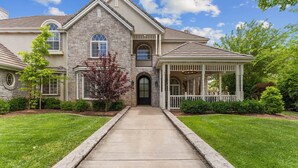 A two-story house with a stone facade, a covered porch, and a well-maintained lawn. - The Country House: 9 Miles to Sand Hollow, HUGE Private Pool, Parking for 13! (Hurricane)