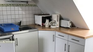 Une cuisine compacte équipée d’un four à micro-ondes, d’un grille-pain, d’une machine à café et d’un petit réfrigérateur.