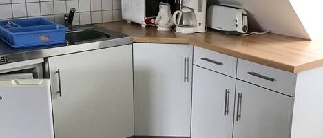 A compact kitchen with a microwave, toaster, coffee maker, and a small refrigerator.