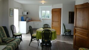 Un espace de vie compact comprenant un coin repas, une kitchenette et une grande porte en bois.