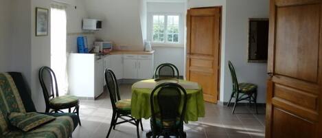 A compact living space with a dining area, kitchenette, and a large wooden door.