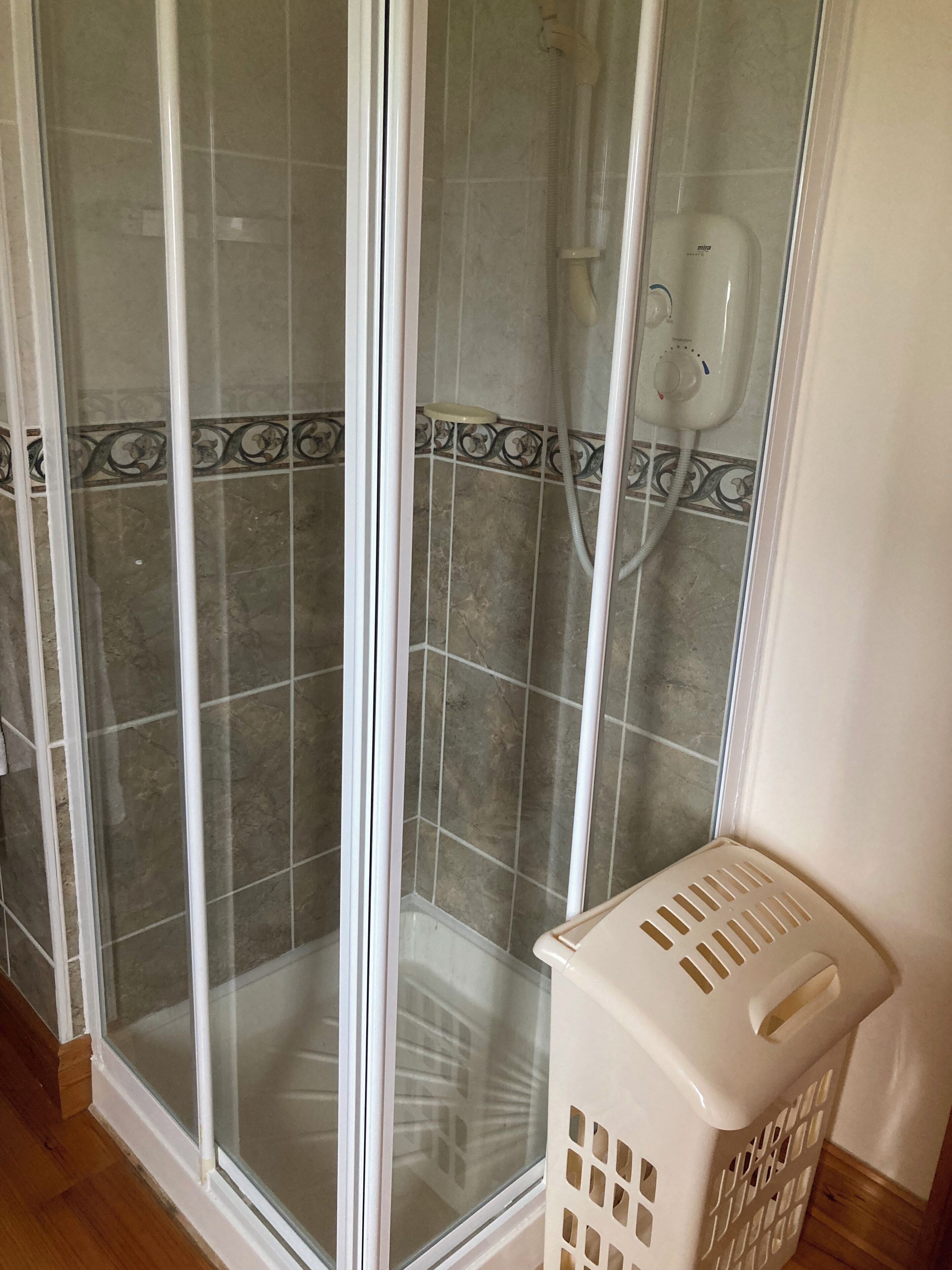 A shower area with a glass door, a showerhead, and a control panel.