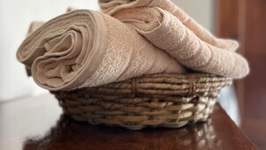Una cesta tejida con toallas beige dobladas sobre una mesa de madera.