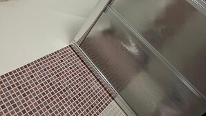 Una esquina de una habitación con pared de piedra y puerta de cristal.
