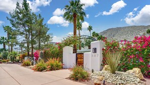 A gated entrance with a number 367 sign, surrounded by cacti, flowering plants, and a mountain backdrop. - The Cove: Heated Pool, BBQ, Walk To Downtown PS (Palm Springs)
