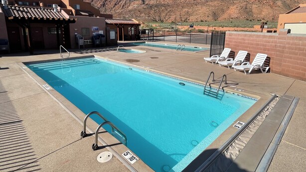 A rectangular pool with a clear blue water, surrounded by lounge chairs and a poolside area. - 17A3 Two Master Suites, Views, Community Pool & Hot Tub (Moab)