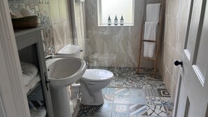 Ein Badezimmer mit Toilette, Waschbecken und einem Fenster mit Flaschen auf der Fensterbank.