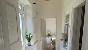 A hallway with a wooden floor, white walls, and a door at the end.