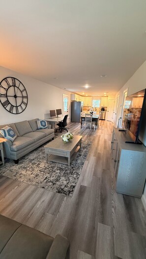 A modern living room with a sofa, coffee table, and a large wall clock. - Modern Spacious Stay, Fast Wi-Fi + Workspace (Hickory)