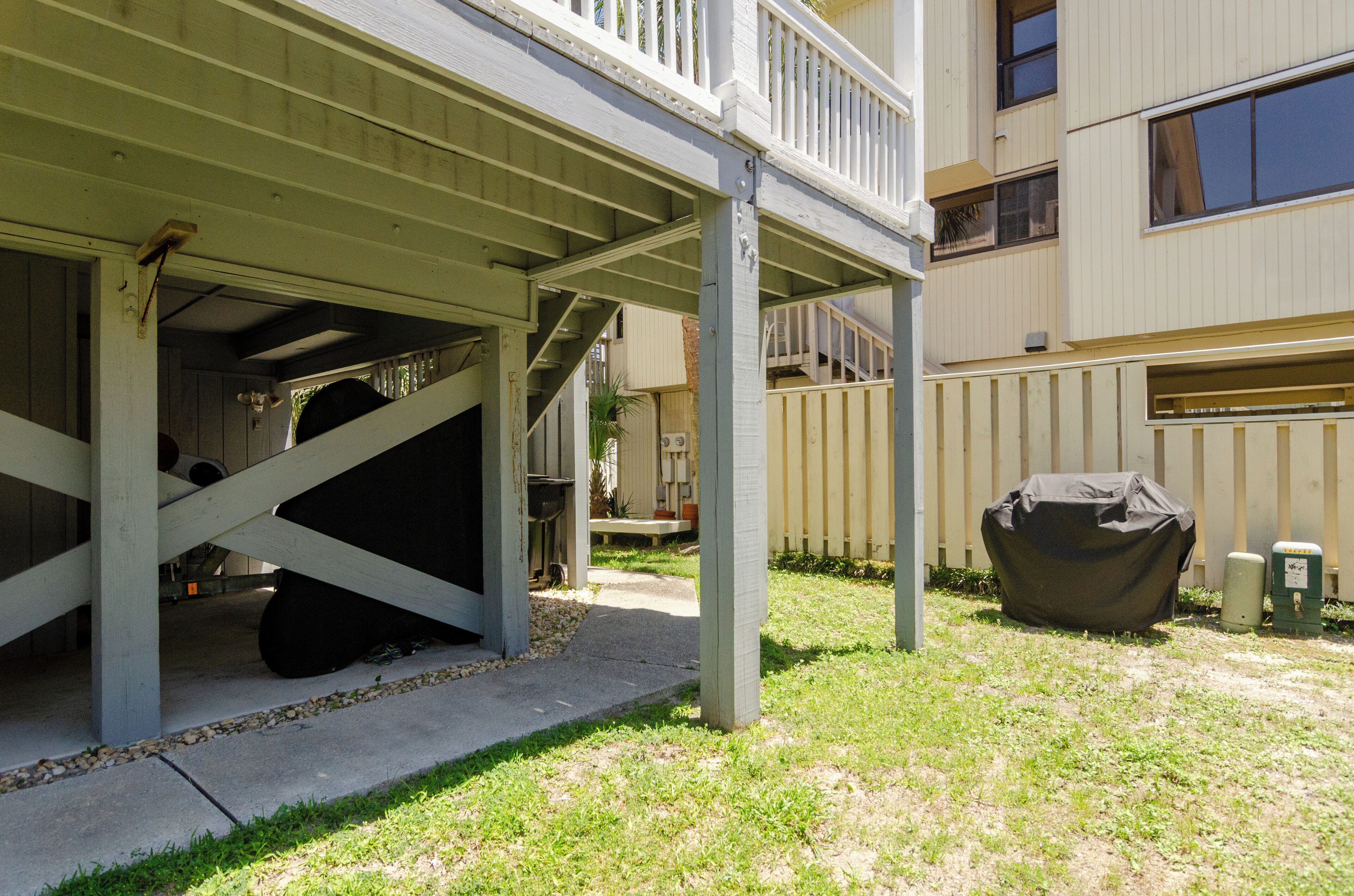A covered outdoor area with a concrete floor, a wooden deck, and a covered object resembling a grill or barbecue.