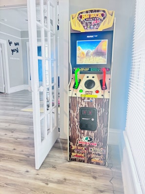 Jogo de arcade de garra com uma máquina de pegar brinquedos, tela exibindo um jogo, joystick vermelho e botão verde.