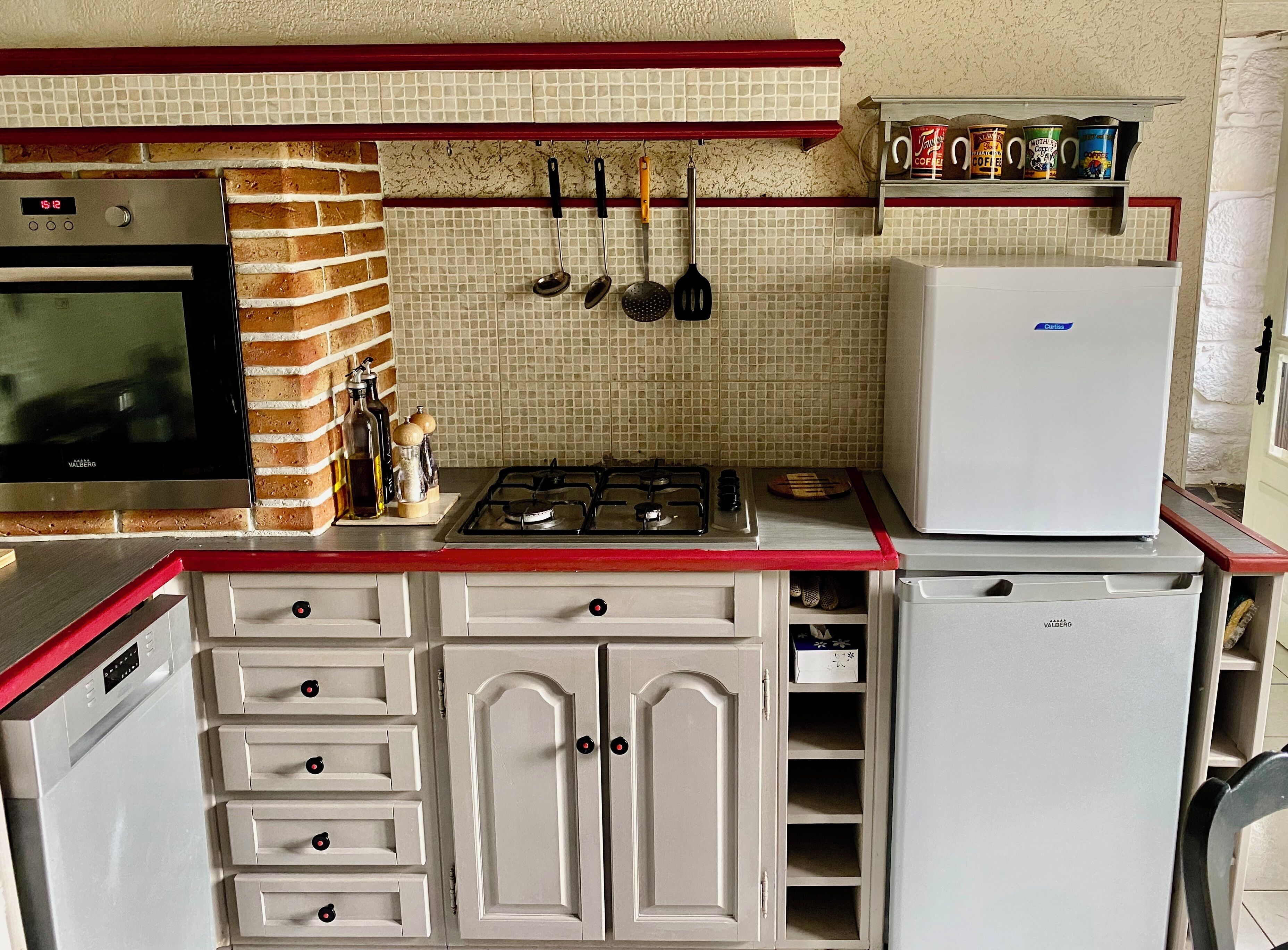 Une cuisine compacte équipée d’une cuisinière à gaz, d’un four encastré, d’un réfrigérateur et d’un four à micro-ondes.
