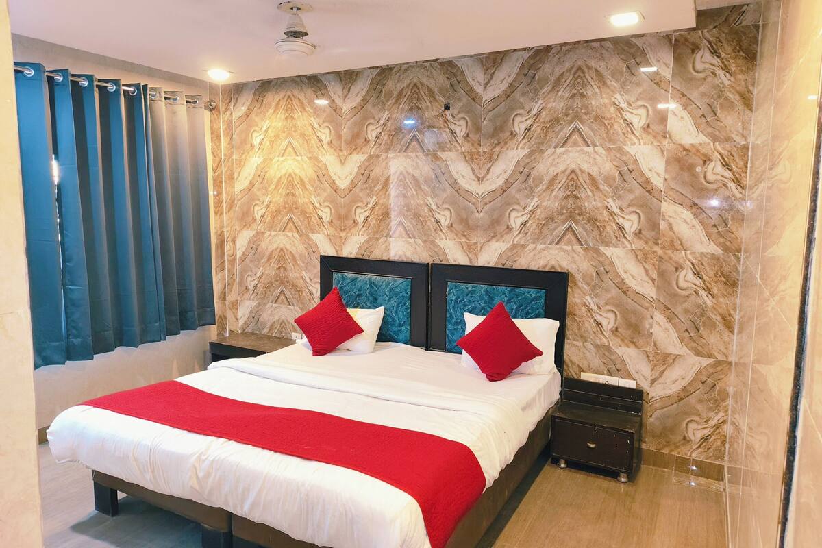 A hotel room with a large bed, marble-patterned walls, and a red and white bedspread.