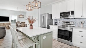 Una cocina moderna con armarios blancos, electrodomésticos de acero inoxidable y una isla central.