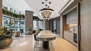 Une cuisine moderne dotée d’un grand îlot en marbre, de luminaires suspendus et offrant une vue sur la ville.