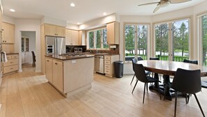 Una cocina moderna con armarios de madera, electrodomésticos de acero inoxidable y un comedor con una mesa grande y sillas.