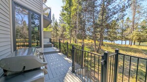 Una terraza con jacuzzi, una escalera y vistas a un lago rodeado de árboles.