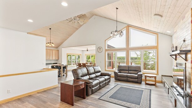 A spacious living room with a high ceiling, leather sofas, a coffee table, and a large window offering a view of the outdoors. - 4BR Lakefront Fishing, Dogs OK Devils Lake (Crary)