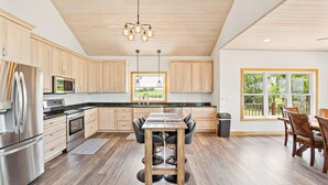 A modern kitchen with wooden cabinets, stainless steel appliances, and a dining area with a table and chairs. - 4BR Lakefront Fishing, Dogs OK Devils Lake (Crary)