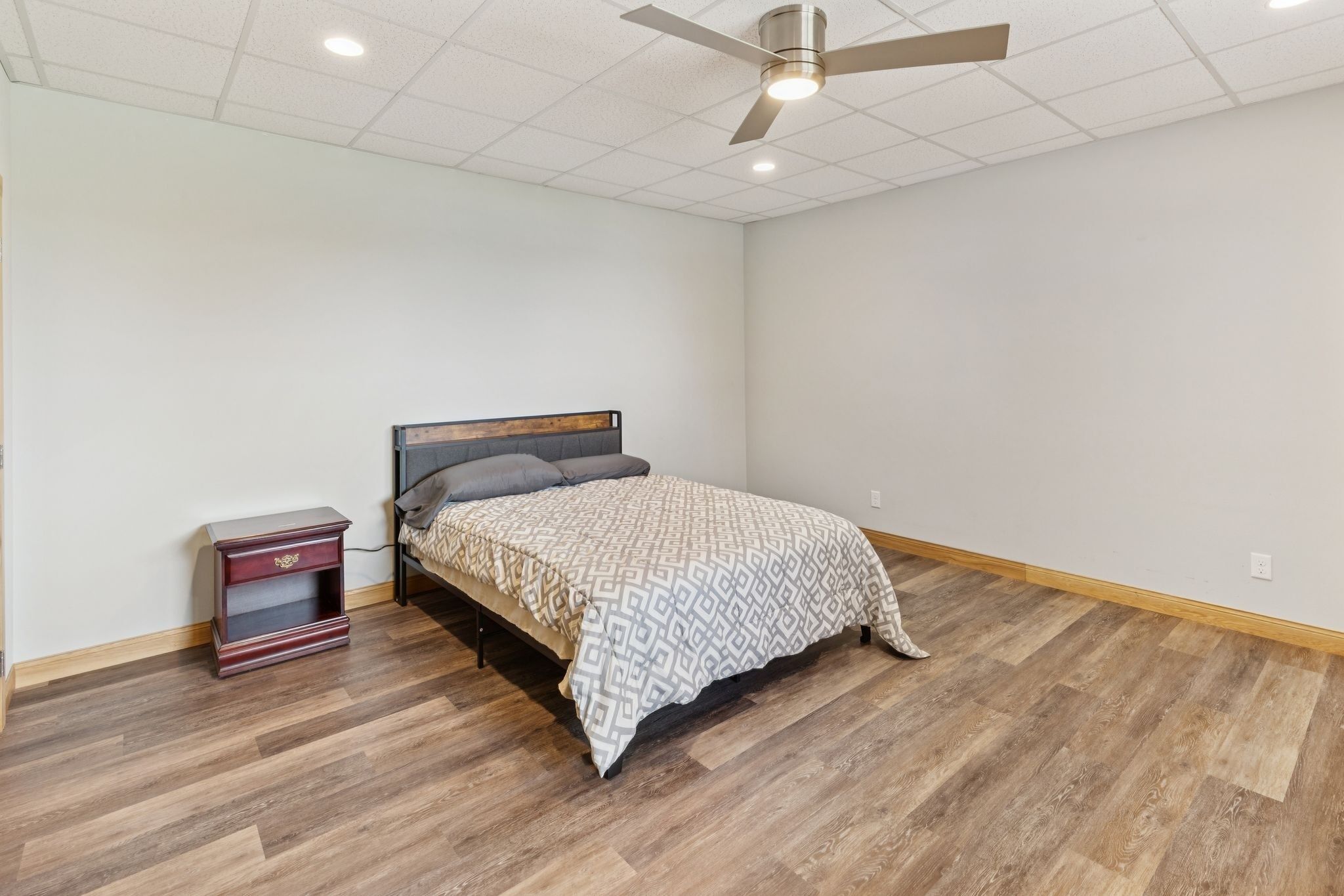 Ein Schlafzimmer mit Bett, Nachttisch und Deckenventilator.