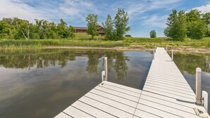 A wooden dock extending into calm water with a house in the background. - 4BR Lakefront Fishing, Dogs OK Devils Lake (Crary)