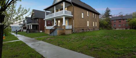 A two-story house with a front porch and a small staircase leading to the entrance.