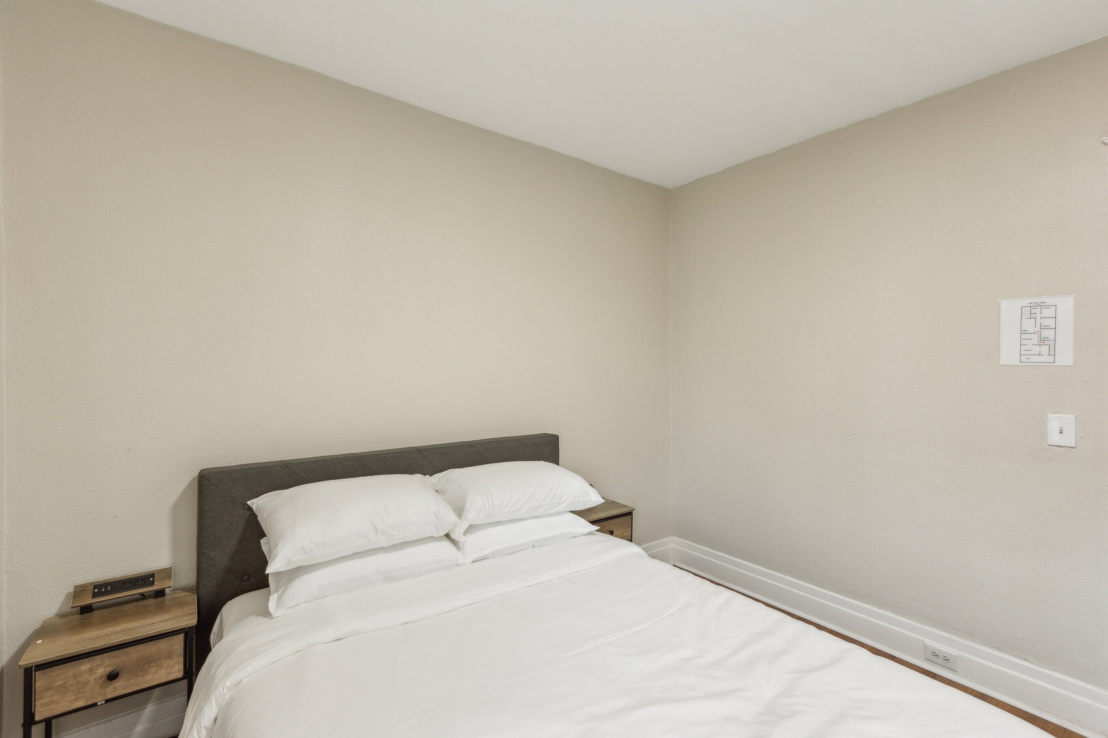 Ein Schlafzimmer mit Bett, Nachttisch und einem an der Wand befestigten Lichtschalter.