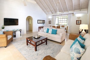 A living room with a sofa, coffee table, and wicker chairs.