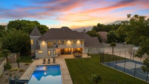 Une maison à deux étages avec une piscine, un terrain de basket et une pelouse bien entretenue.