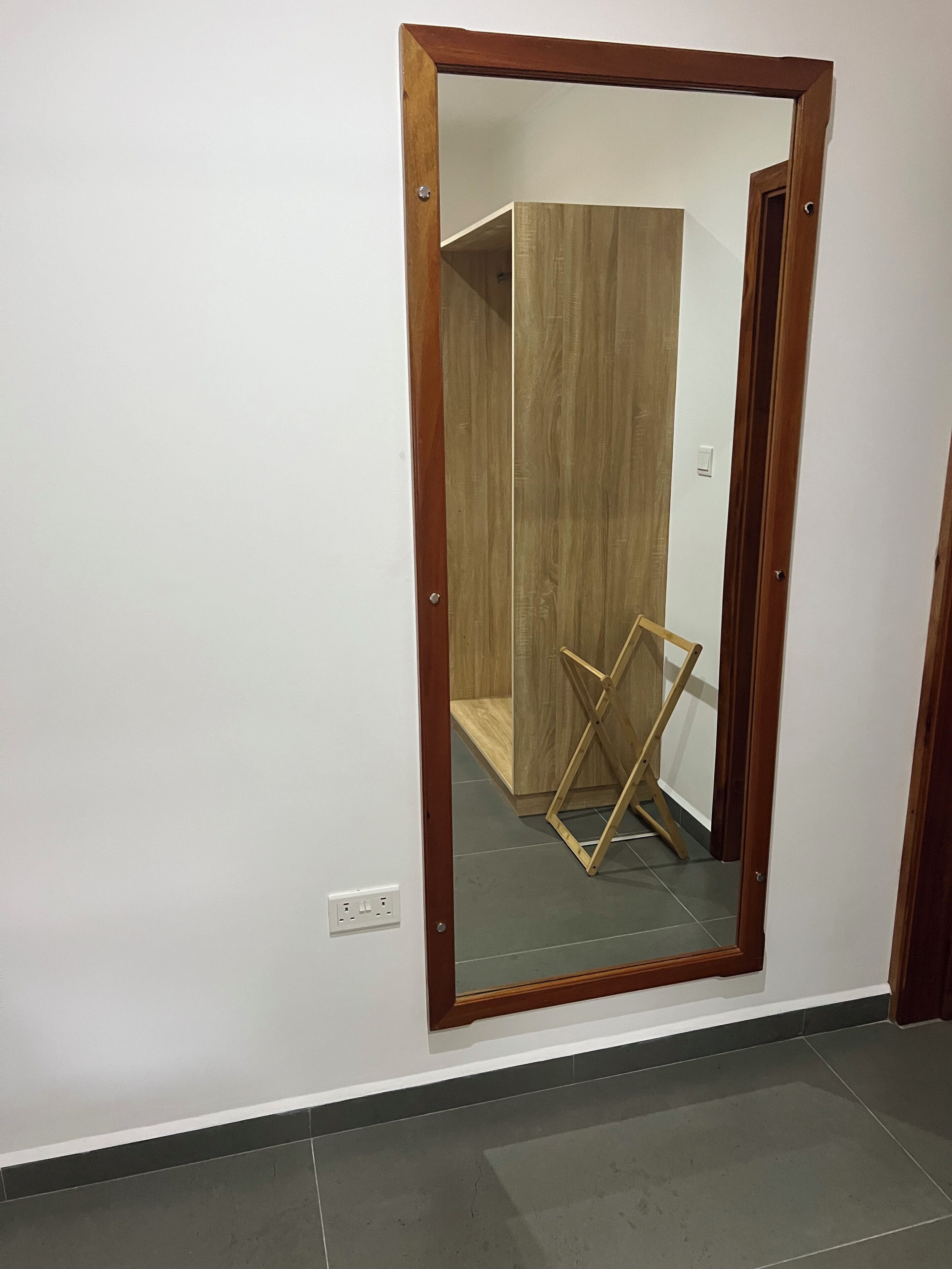 Ein Zimmer mit einem großen Spiegel, einem Holzschrank und einem Holzstuhl.