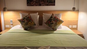Una habitación de hotel con una cama, un cuadro en la pared y una mesita de noche con una lámpara.