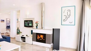 Un salon moderne avec une cheminée, un téléviseur et une œuvre d’art minimaliste.