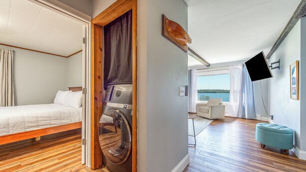 Een kamer met een bed, een wasmachine, een bank en uitzicht op de omgeving.
