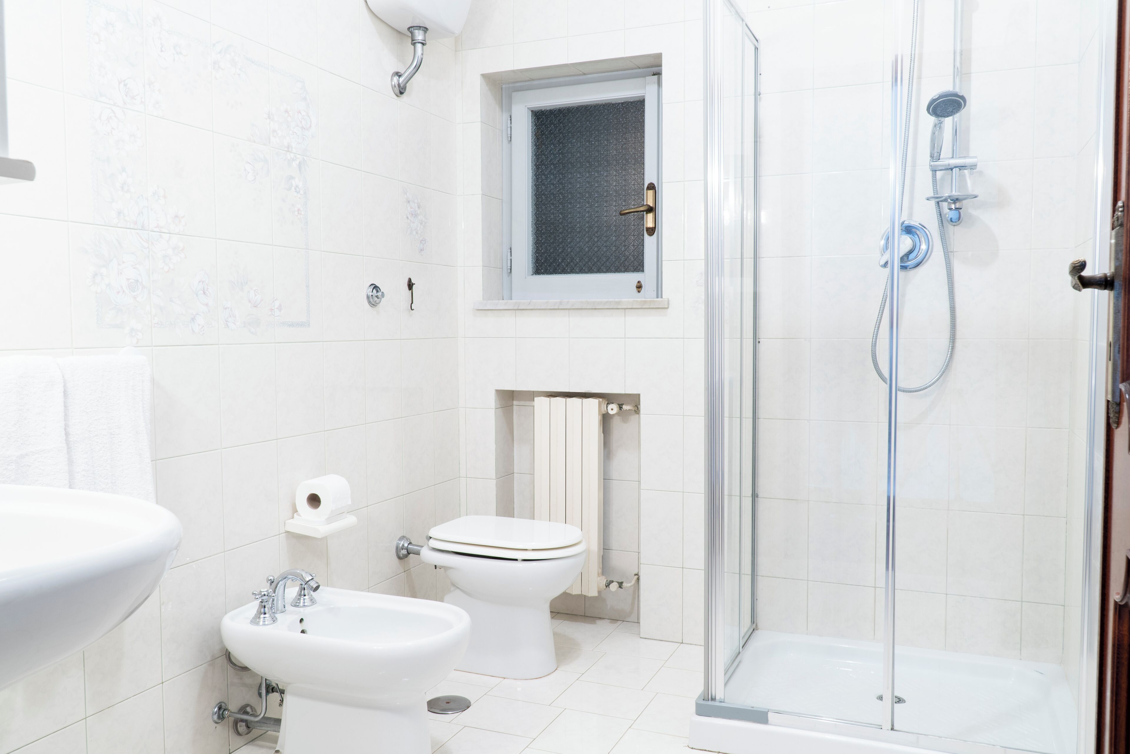 A bathroom with a sink, bidet, toilet, and a glass-enclosed shower area.