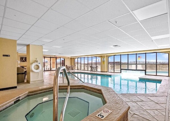 An indoor swimming pool with clear views of the surrounding landscape, a lifebuoy, and a poolside seating area.