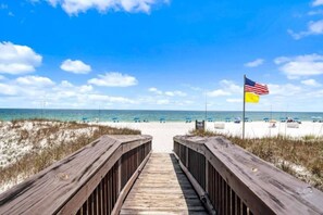 Una passerella in legno che conduce a una spiaggia con una bandiera americana.