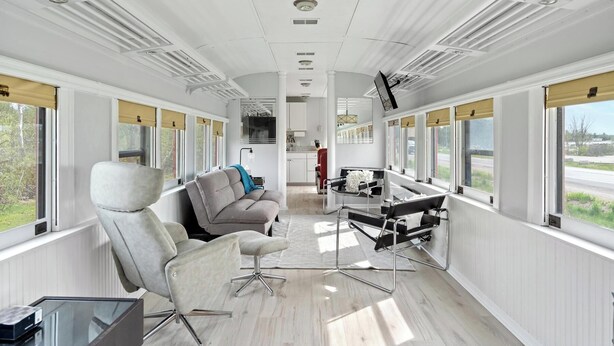 A modern interior with a sofa, armchairs, a glass table, and a piano. - Crooked Lake Express (Alanson)