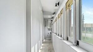 A corridor with white walls, a radiator, and a row of windows with blinds. - Crooked Lake Express (Alanson)