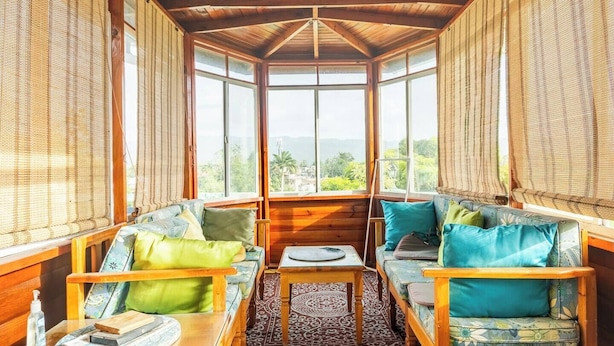Ein gemütliches Zimmer mit Holzwänden und hoher Decke, mit einer Sitzecke mit gepolsterten Bänken und einem kleinen Tisch.