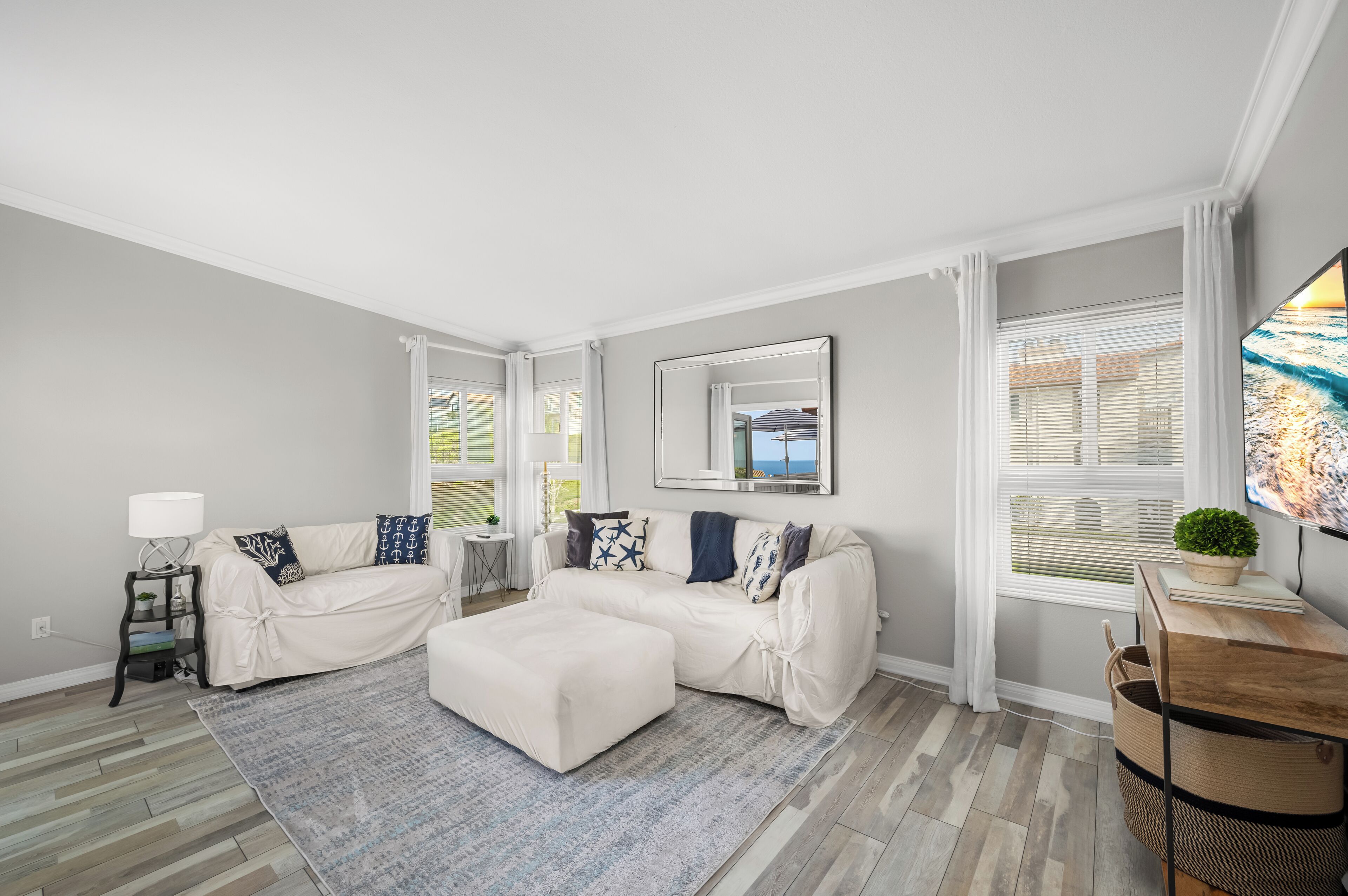 A modern living room with a sectional sofa, a coffee table, and a large window with blinds.