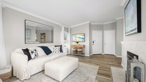 Una sala moderna con un sofá blanco, un reposapiés y una chimenea.