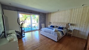 Ein Schlafzimmer mit einem großen Bett, einer Schiebetür zum Patio und einem Holzboden.