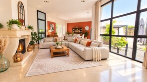 A spacious living room with a fireplace, large windows, and a cozy seating area. - Magnificent villa with a pool and spa near Bordeaux (La Brède)