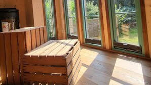 A room with large windows, wooden flooring, and a wooden bench. - Tiny House Design in a Vacation Park Near an Eco-Village (Steyerberg)