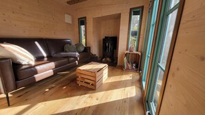 A cozy wooden interior with a leather sofa, a wooden coffee table, and a fireplace. - Tiny House Design in a Vacation Park Near an Eco-Village (Steyerberg)