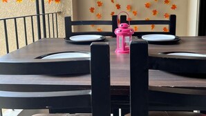 A dining table with chairs, a pink lantern, and autumn leaf decorations on the wall. - 2-bedroom apartment in delightful Manipal with AC, WiFi, fitness room (Manipal)
