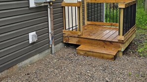 A building with a wooden deck, a door, and electrical boxes. - Charming 2-bedroom cottage in Beautiful Milford Center with WiFi, AC (Milford Center)